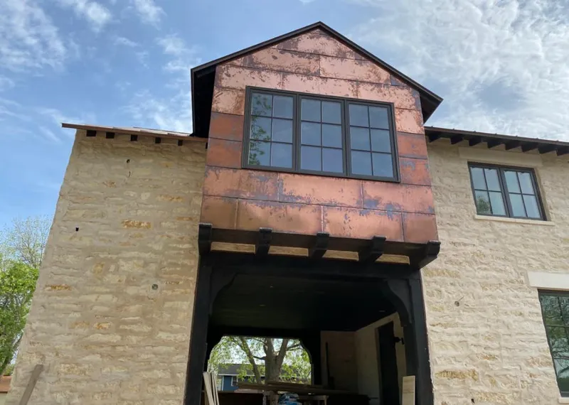 Copper metal panel facade on a stone building for Roof Repair in Allendale